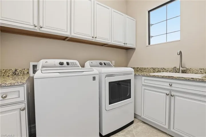 Washroom featuring cabinet space, independent washer and dryer, and light tile patterned floors