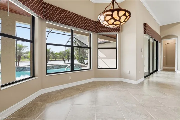 Unfurnished dining area featuring ornamental molding, a water view, arched walkways, and light tile patterned floors