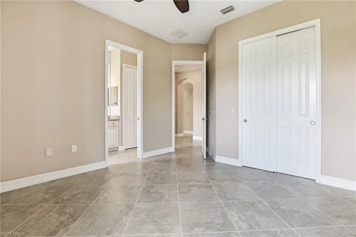Unfurnished bedroom with ceiling fan, arched walkways, and a closet