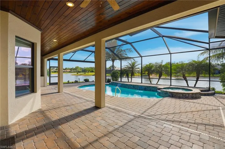 View of swimming pool featuring a patio, a water view, glass enclosure, a pool with connected hot tub, and a sunroom