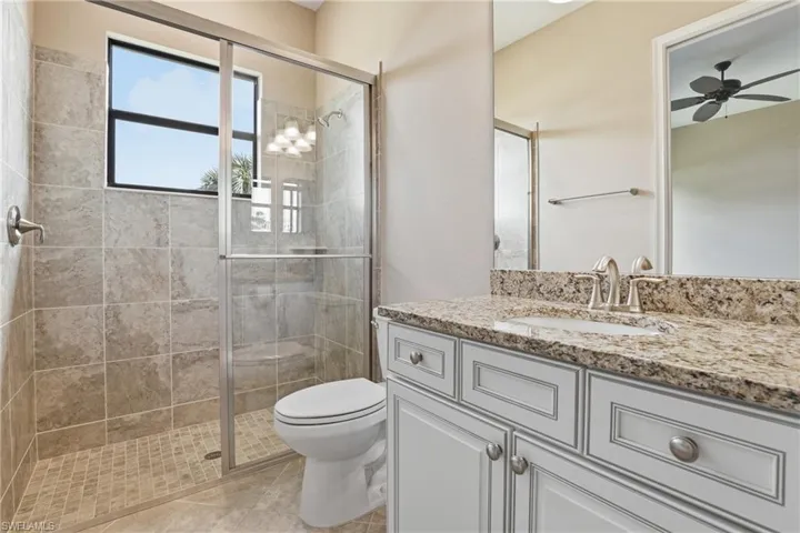 Full bathroom with vanity, a stall shower, and a ceiling fan