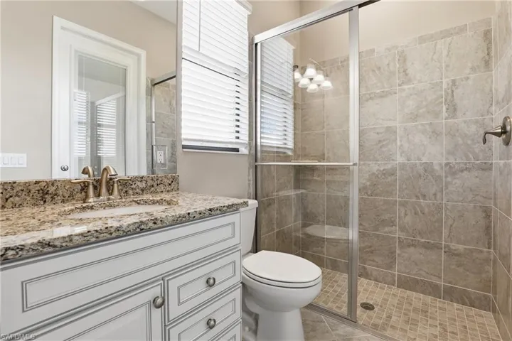 Bathroom featuring vanity, a shower stall, and a chandelier