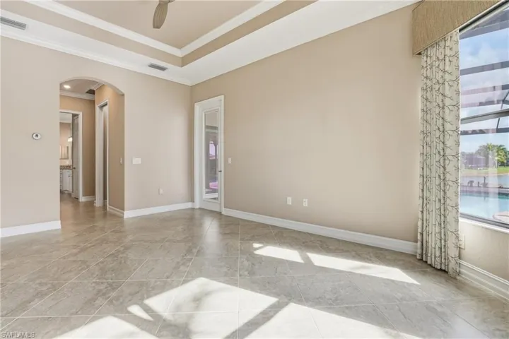 Unfurnished room featuring arched walkways, ornamental molding, and a ceiling fan