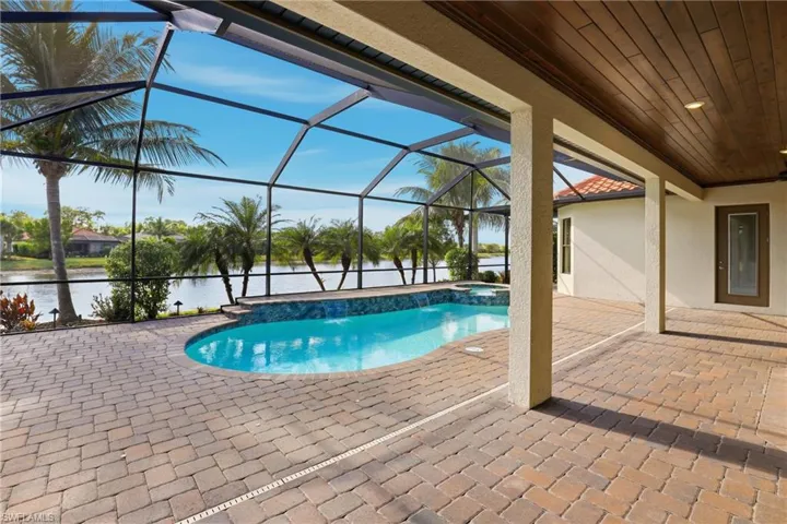 View of pool with a patio area, glass enclosure, a sunroom, a water view, and a pool with connected hot tub