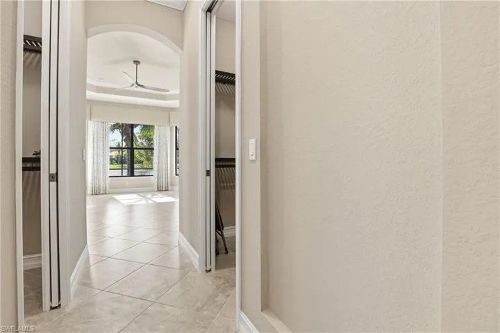 Hallway with a raised ceiling, arched walkways, and light tile patterned flooring