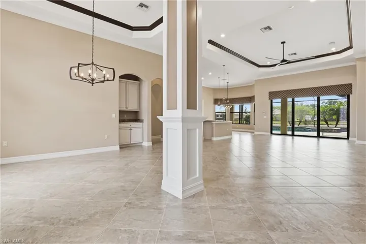 Unfurnished living room with a chandelier, ornamental molding, a raised ceiling, ceiling fan, and arched walkways