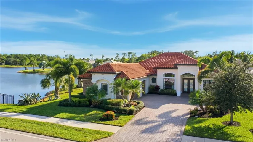 Mediterranean / spanish house with french doors, a front yard, decorative driveway, a water view, and a tiled roof