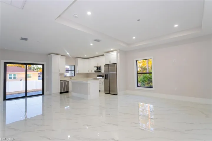 Kitchen with open floor plan, a kitchen island, stainless steel appliances, white cabinets, and a raised ceiling