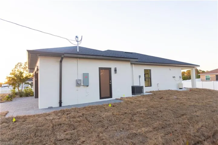 Back of house with stucco siding and roof with shingles