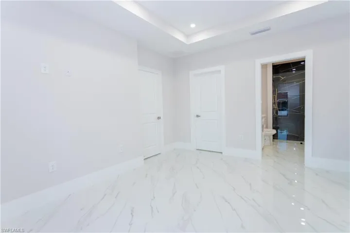 Unfurnished bedroom featuring a spacious closet, a tray ceiling, and recessed lighting