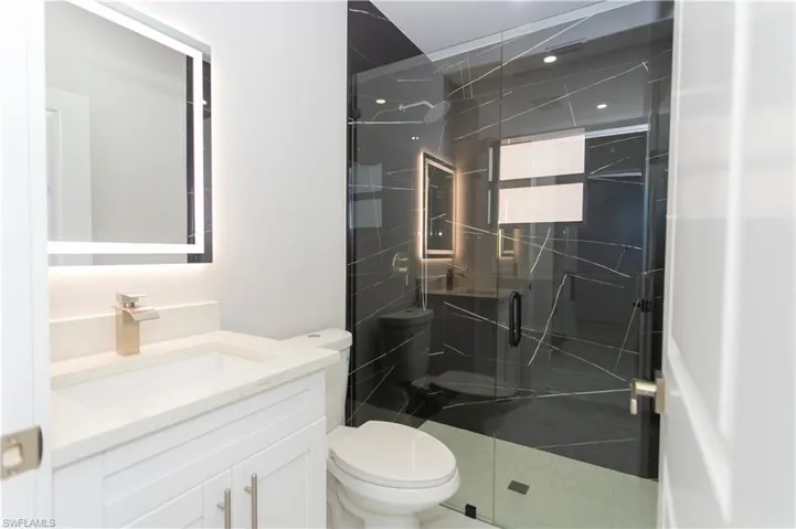 Bathroom featuring a marble finish shower and vanity