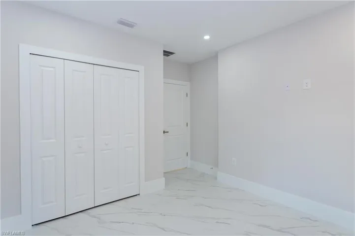 Unfurnished bedroom with light marble finish floors, a closet, and recessed lighting