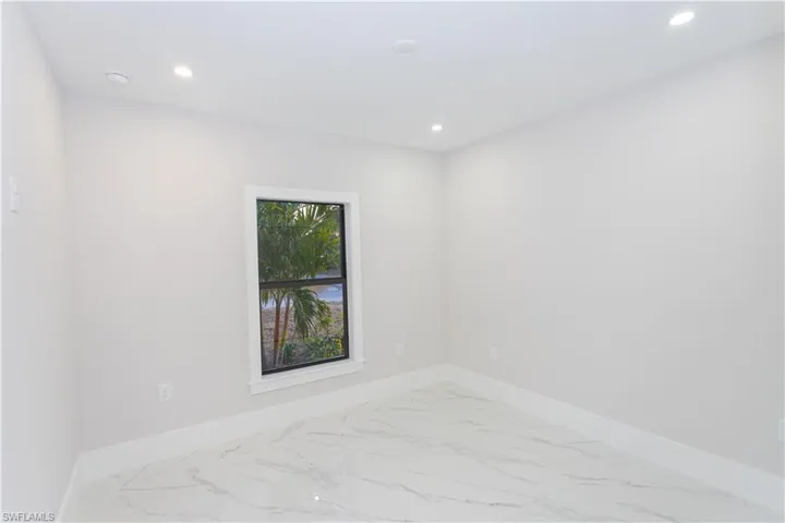 Empty room with marble look tile flooring and recessed lighting