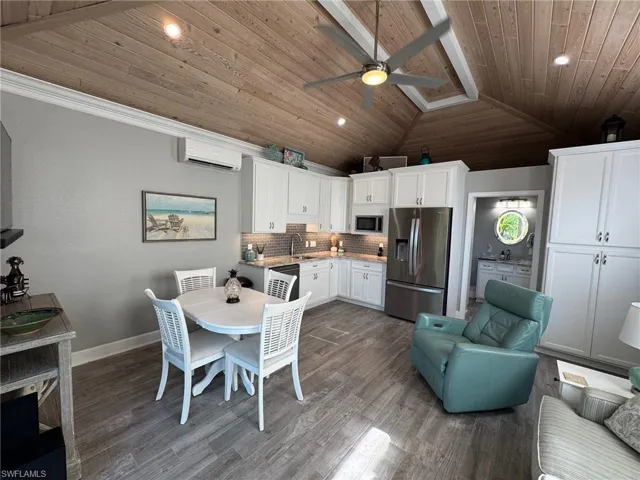 Dining area with an AC wall unit, hardwood / wood-style floors, ceiling fan, wooden ceiling, and lofted ceiling