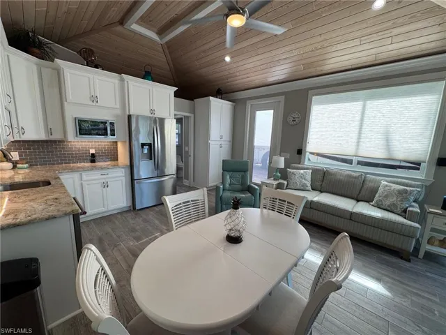 Dining room with dark wood-type flooring, wooden ceiling, sink, vaulted ceiling, and ceiling fan