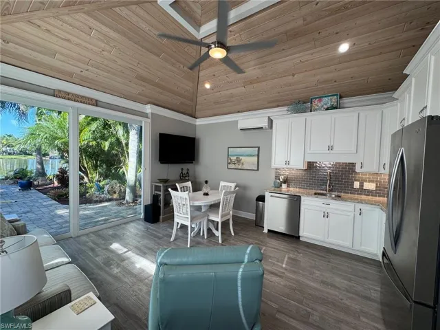 Kitchen with white cabinets, a wall mounted AC, high vaulted ceiling, dark wood-type flooring, and stainless steel appliances