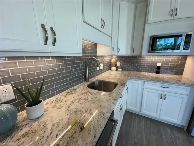 Kitchen featuring white cabinetry, light stone countertops, sink, and dark hardwood / wood-style floors