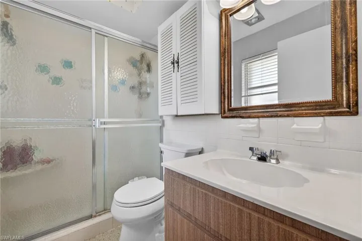Bathroom with vanity, tile walls, a shower stall, and decorative backsplash