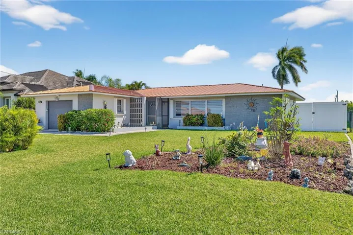 Ranch-style home featuring brick siding, an attached garage, a front yard, and a metal roof