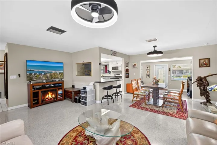 Living area with ceiling fan and a warm lit fireplace