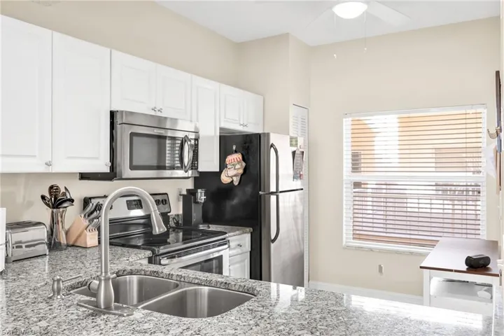 Kitchen featuring appliances with stainless steel finishes, white cabinets, and granite counters