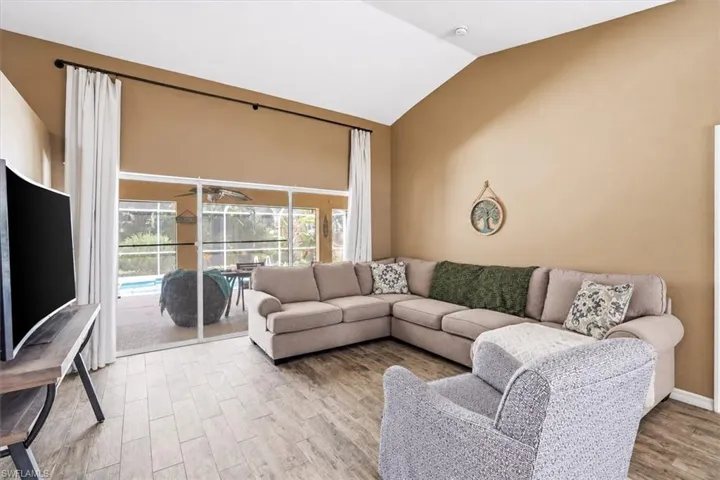 Vaulted ceiling, wood-finish flooring, sliding glass doors, screened patio, and swimming pool