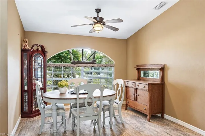 Vaulted ceiling with a ceiling fan, arched window with horizontal blinds, and wood-finish flooring