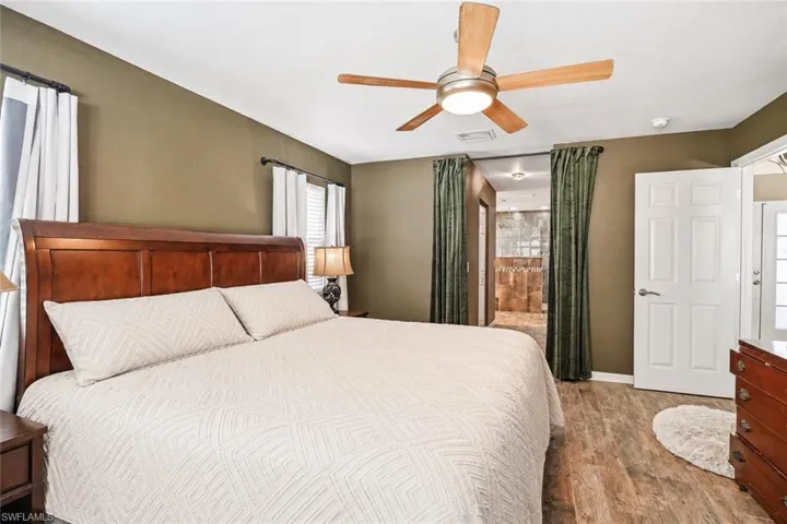 Wood-finish flooring, ceiling fan with integrated lighting, wood panel doors, and window treatments