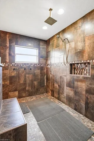 Walk-in shower with full-height tile, a recessed shower niche, and a fixed rain shower head