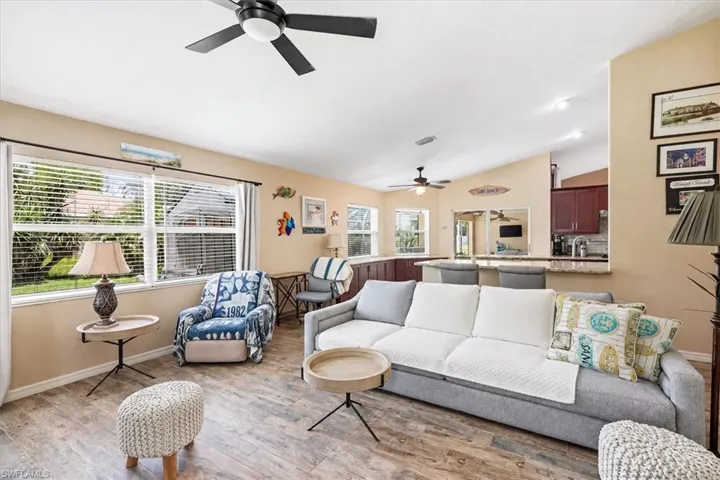 Open-concept living area featuring wood-finish flooring, vaulted ceilings, and a ceiling fan