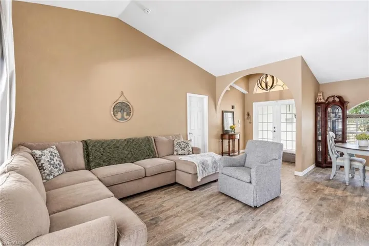 Vaulted ceilings, wood-finish flooring, arched entryway, and double French doors with transom window