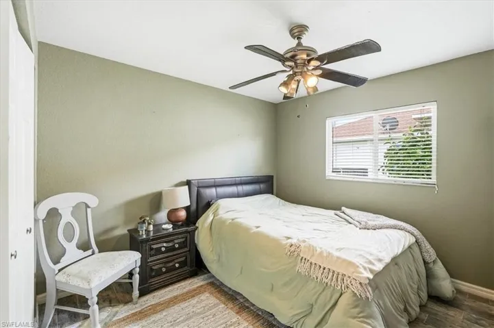 Window with blinds, wood-finish flooring, and a ceiling fan with integrated lighting