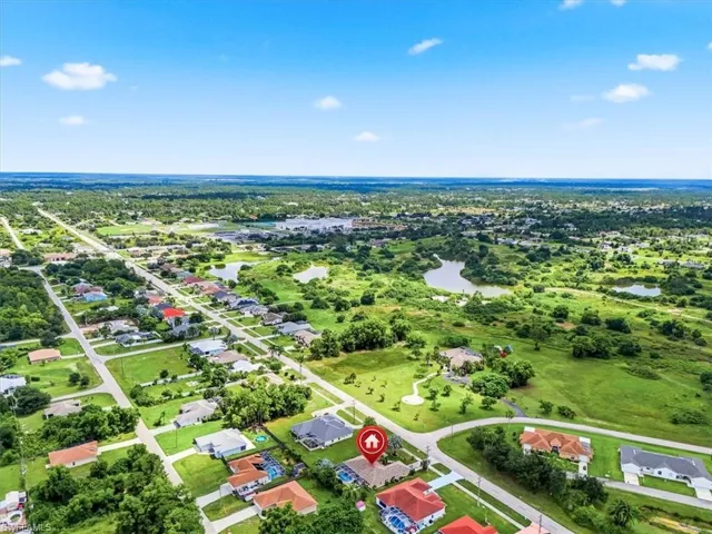 Aerial perspective of a residential area with varied housing styles, surrounded by green landscapes and multiple bodies of water