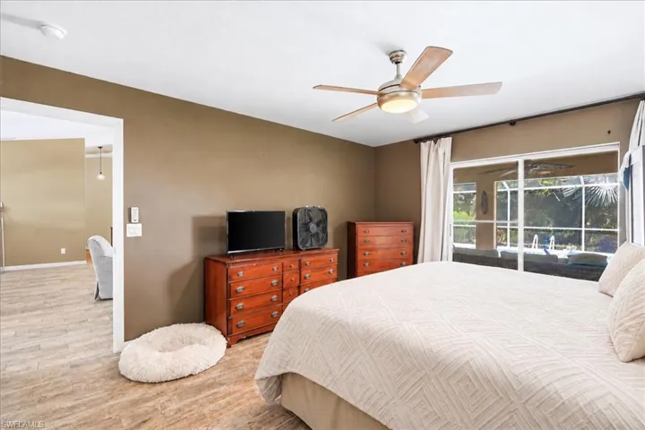 Wood-finish flooring throughout, ceiling fan with integrated lighting, sliding glass door to exterior, exterior screened enclosure, and neutral wall paint