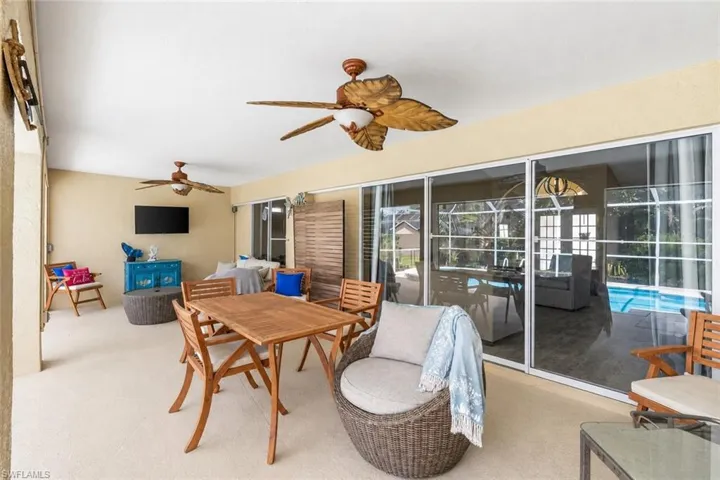Bright and open living area featuring polished concrete flooring, ceiling fans with decorative bronze finishes, and expansive sliding glass doors opening to outdoor space