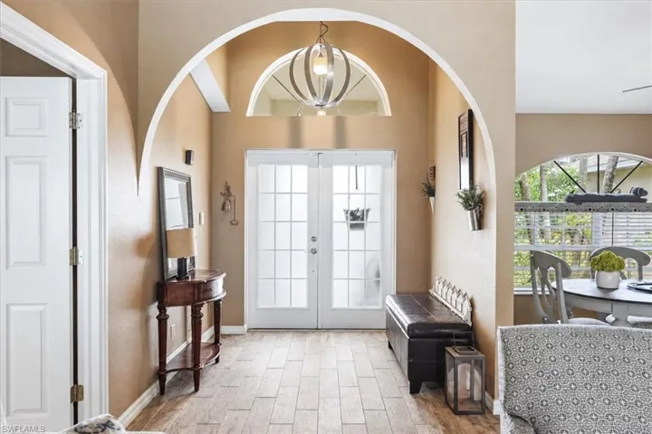 Entryway featuring wood-finish flooring, a decorative arched doorway, double glass-paneled entry doors, and an arched transom window
