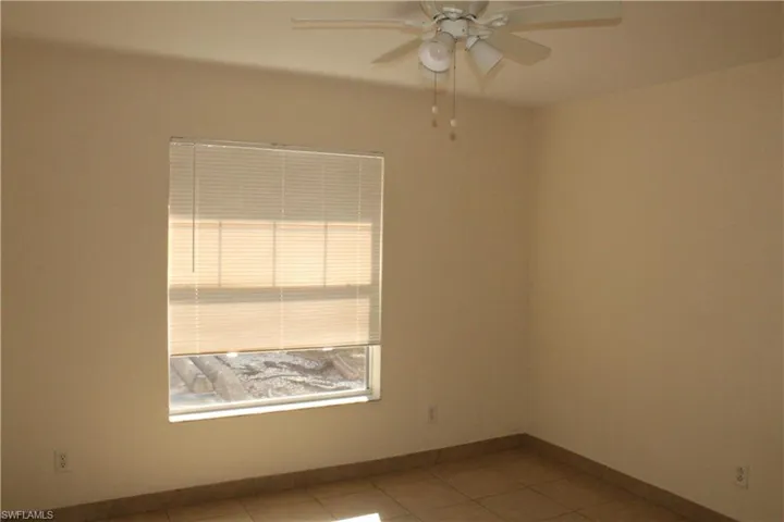 Empty room with light tile patterned floors and a ceiling fan