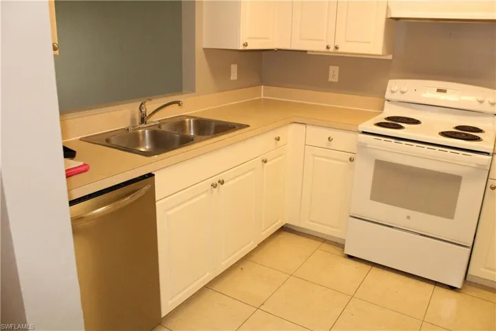 Kitchen with white range with electric cooktop, dishwasher, light countertops, and white cabinetry