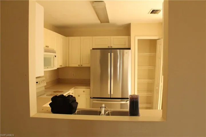 Kitchen with white appliances, white cabinets, and light countertops