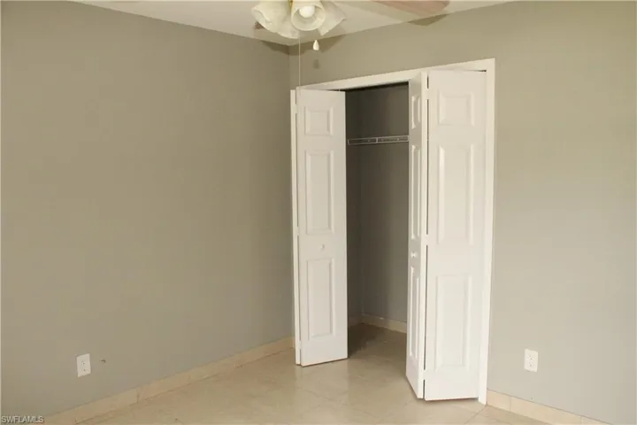 Unfurnished bedroom featuring ceiling fan, a closet, and light tile patterned floors