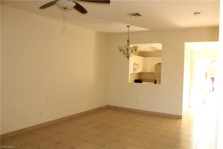 Unfurnished room with ceiling fan, a chandelier, and light tile patterned floors