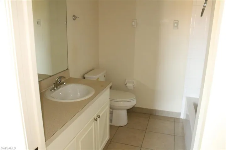 Full bath with vanity, light tile patterned flooring, and bathtub / shower combination