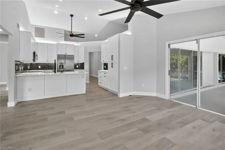 Kitchen featuring a ceiling fan, a peninsula, stainless steel refrigerator with ice dispenser, recessed lighting, and open floor plan