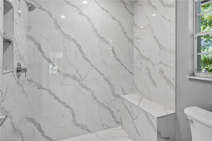 Primary bathroom shower with marble looking tile