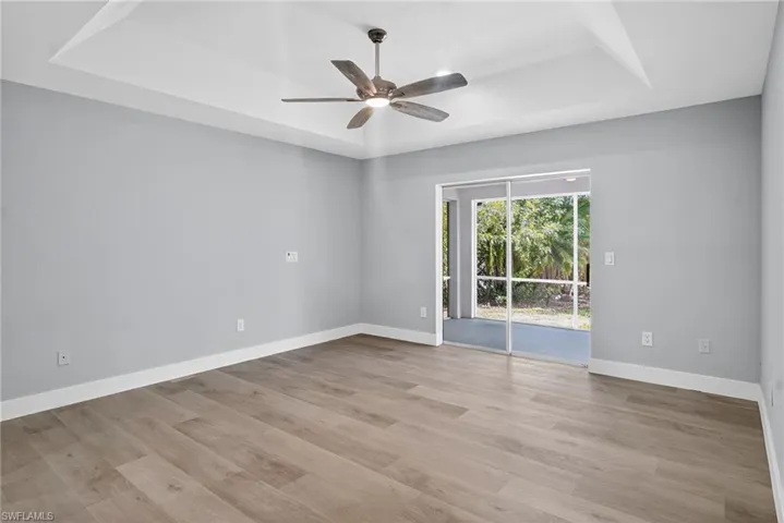Primary bedroom featuring a tray ceiling, with ceiling fan, and pocket sliding doors.
