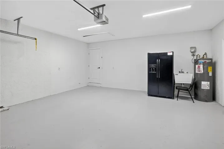 Garage featuring sink, electric water heater, and a garage door opener.
