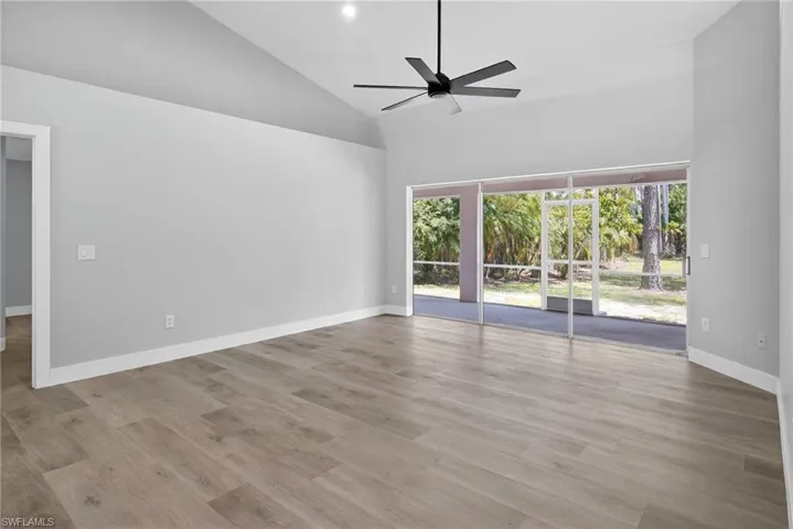Living room with high vaulted ceiling, pocket sliding doors, ceiling fan, and recessed lighting