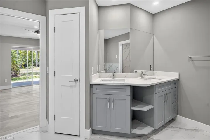 Full bath featuring double vanity with wood cabinetry and Quartz tops, marble look flooring, and recessed lighting