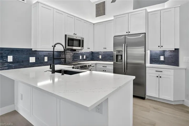 Kitchen featuring a peninsula, stainless steel appliances, light Quartz counters, and decorative backsplash