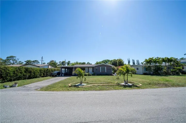View of front of property featuring a carport, driveway, and a front lawn